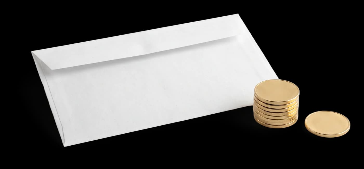 Envelope branco ao lado de uma pilha de moedas douradas